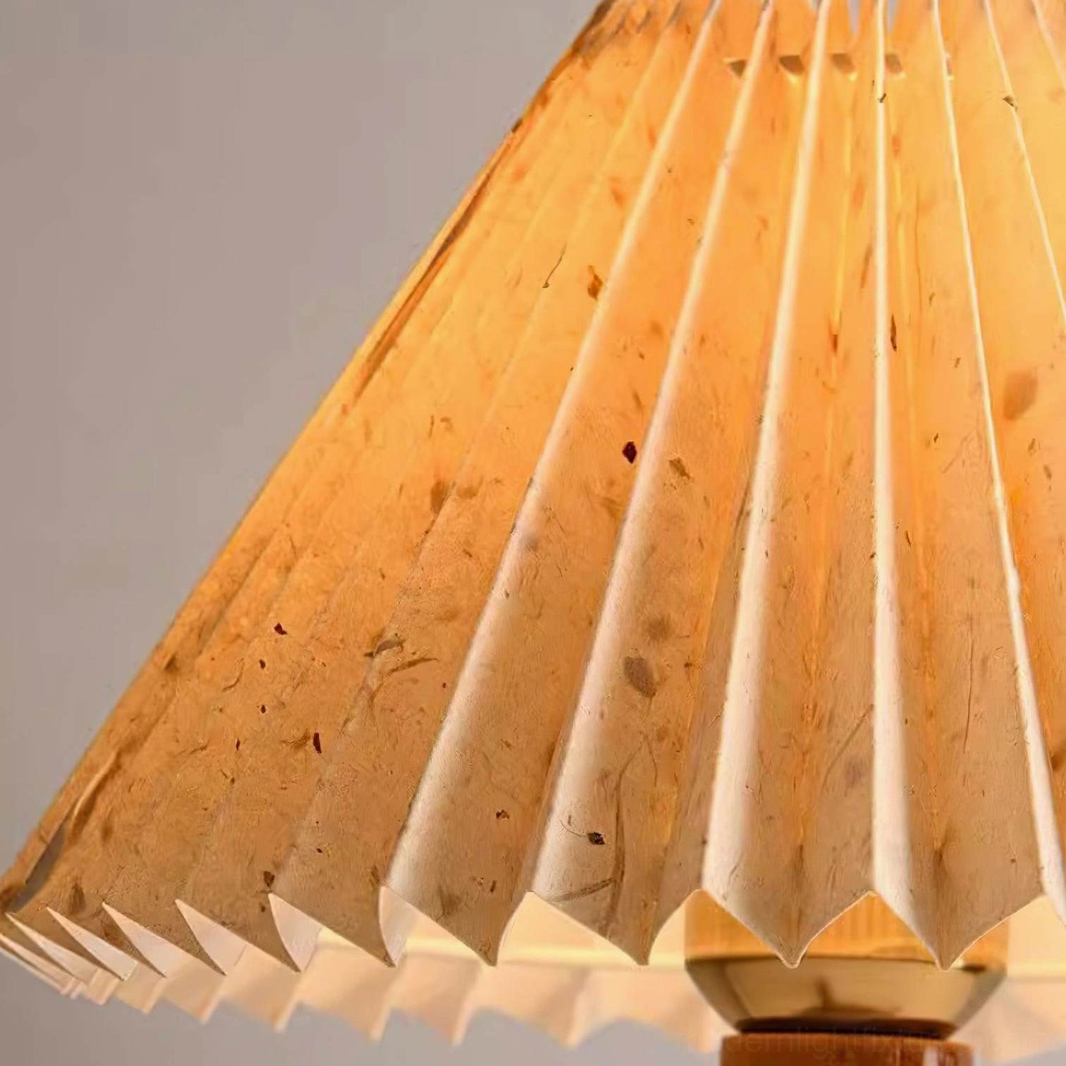 Pleated table lamp with wooden tripod base casting soft diffused light for ambient home lighting