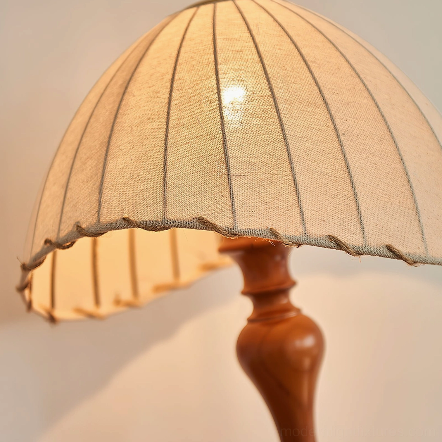 Close-up of pleated linen shade with warm internal lighting, table lamp detail shot