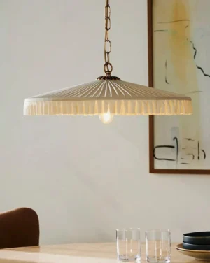 Pleated pendant light illuminated from below in dining room, warm LED bulb glow through fabric
