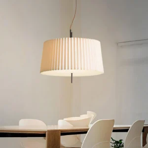 Modern white pleated pendant light hanging above dining table with white chairs in Scandinavian interior design