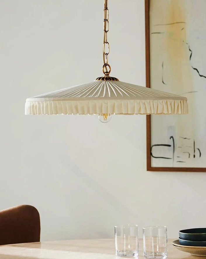 Hand-pleated fabric pendant shade hung over dining table with place settings