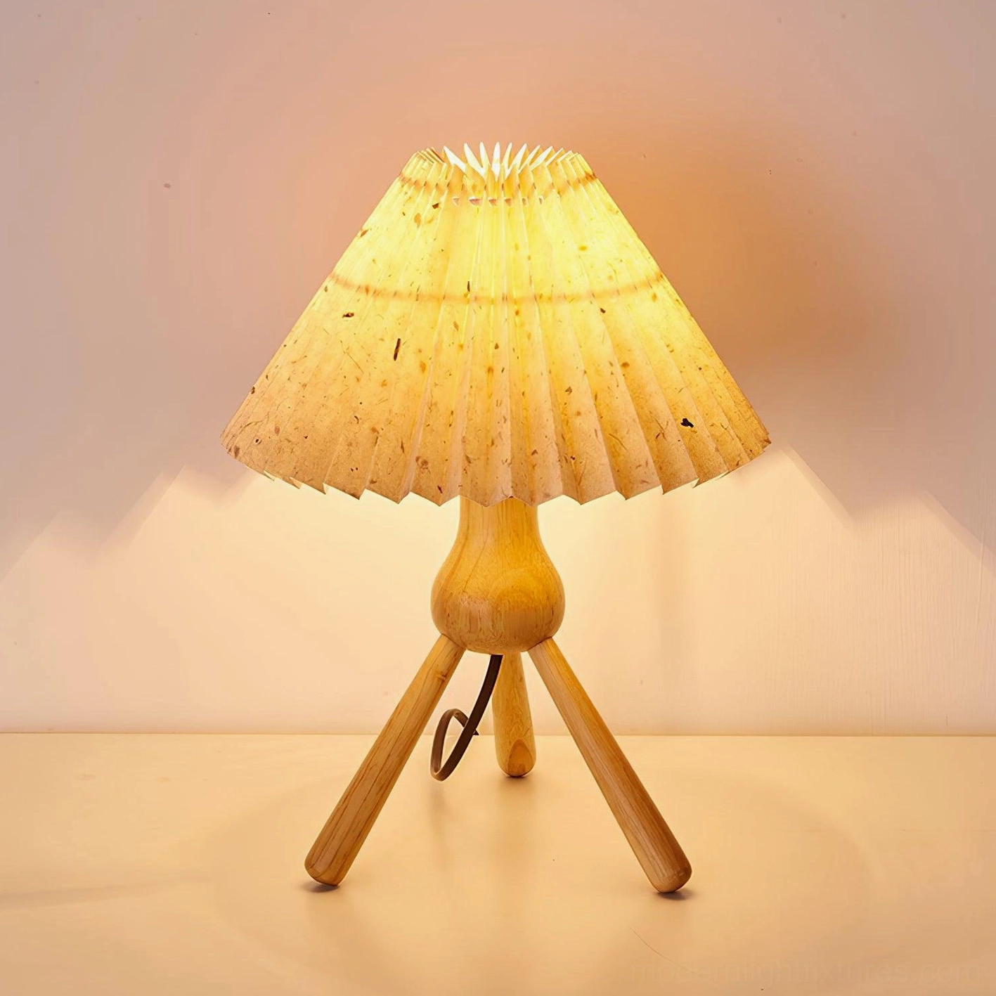 Close-up detail of pleated fabric shade on tripod table lamp with natural wood tripod base