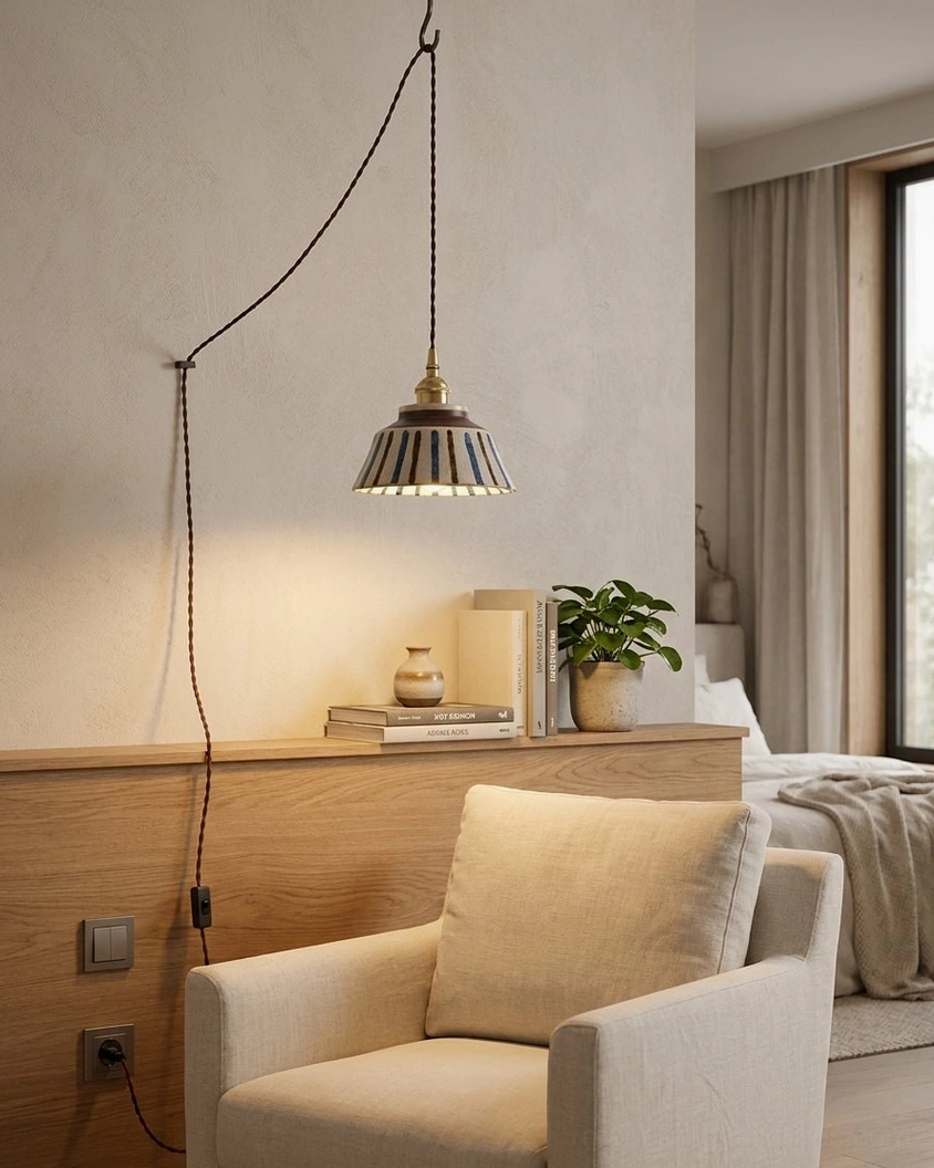 Grey pleated fabric shade plug-in pendant lamp with brass accents in cozy bedroom lounge area