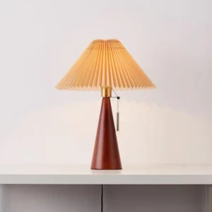 Wooden table lamp with accordion pleated shade, eye-level studio view showing pull chain switch and metal detail