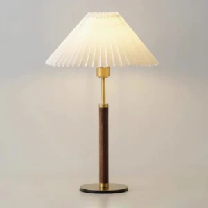 Close-up detail of pleated table lamp shade structure and walnut wood base with metal accents
