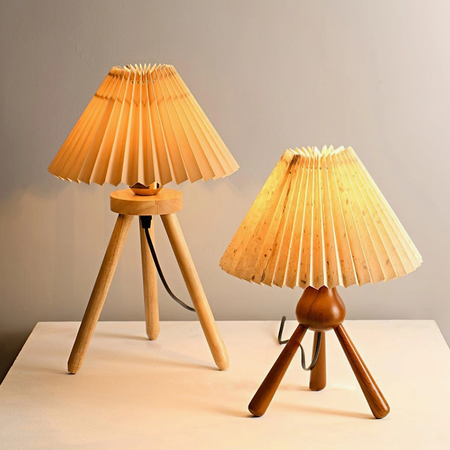 Comparison of two pleated tripod table lamps in walnut and natural wood finishes, side by side