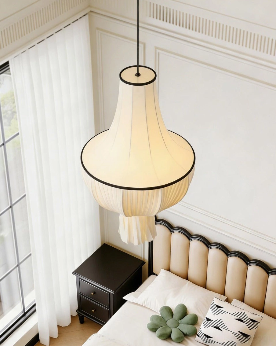 Plisselle pleated pendant light hanging in cozy master bedroom, eye-level angled view over nightstand, warm neutral bedroom decor with soft bedding
