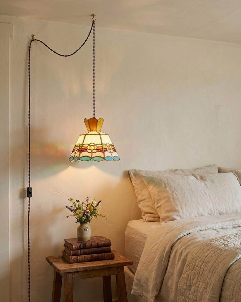 Retro stained glass plug-in pendant light hanging in bedroom corner above side table displaying hand-cut glass panels with vintage cottagecore aesthetic and warm brass frame