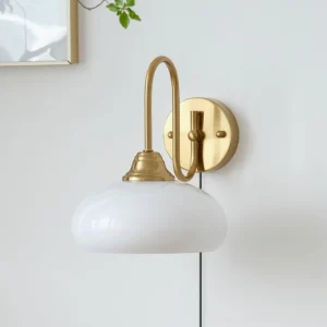 Mid-century plug-in wall sconce with brass gold hardware and ribbed glass shade mounted on white wall with framed artwork