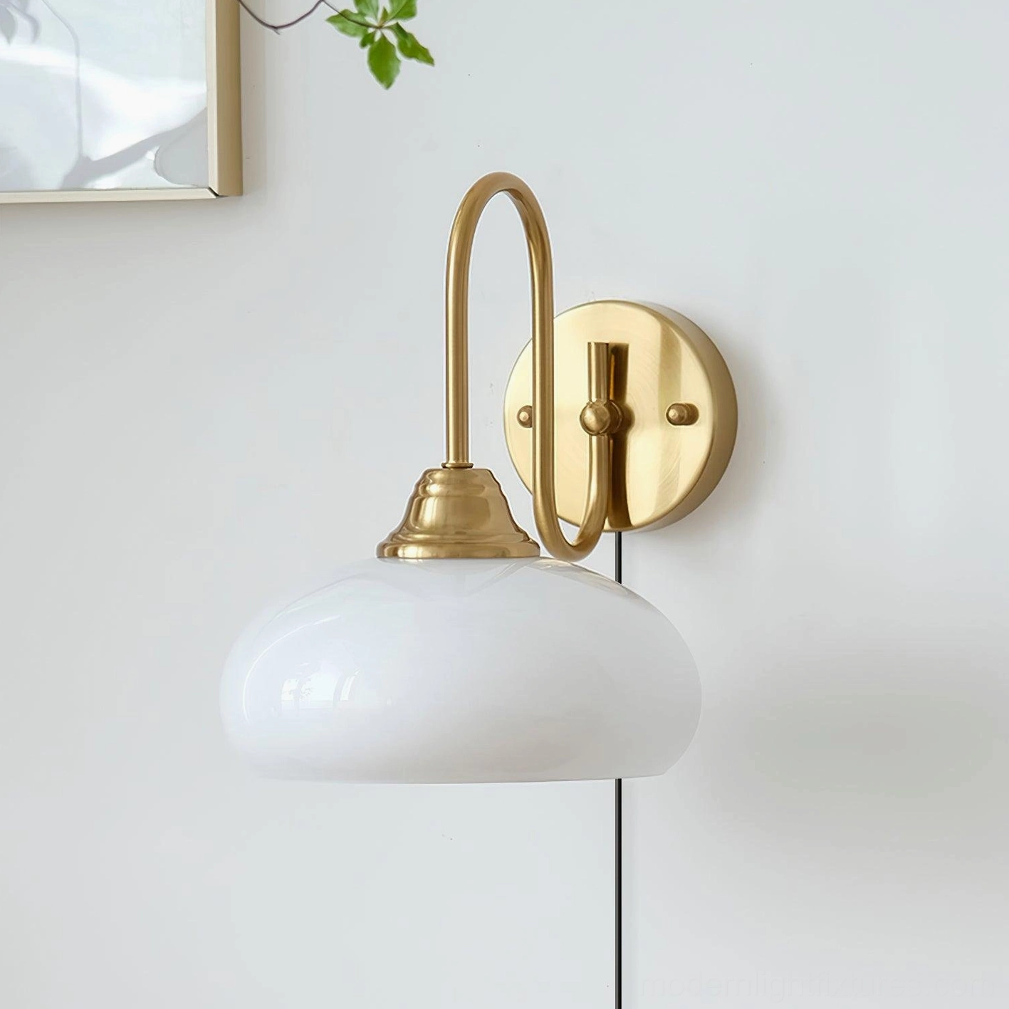 Mid-century plug-in wall sconce with brass gold hardware and ribbed glass shade mounted on white wall with framed artwork