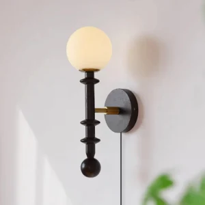 Illuminated wood and brass wall sconce mounted on interior wall with ambient warm light glow in minimalist home setting