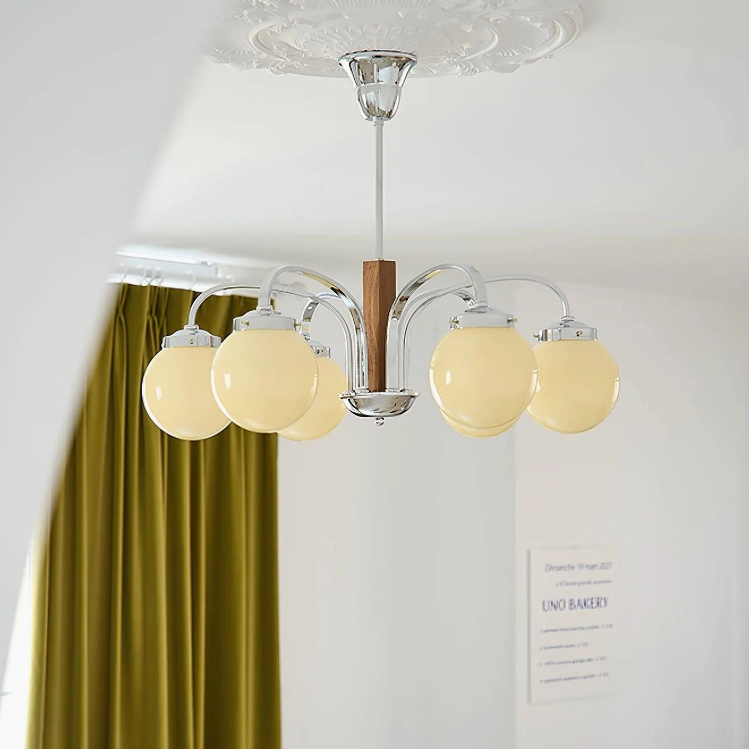 Polaris Bauhaus chandelier illuminated overhead view in living room with green velvet curtains warm ambient lighting