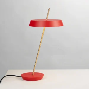 Side profile of red Poldina contemporary table lamp showing elegant brass support rod and round metal base