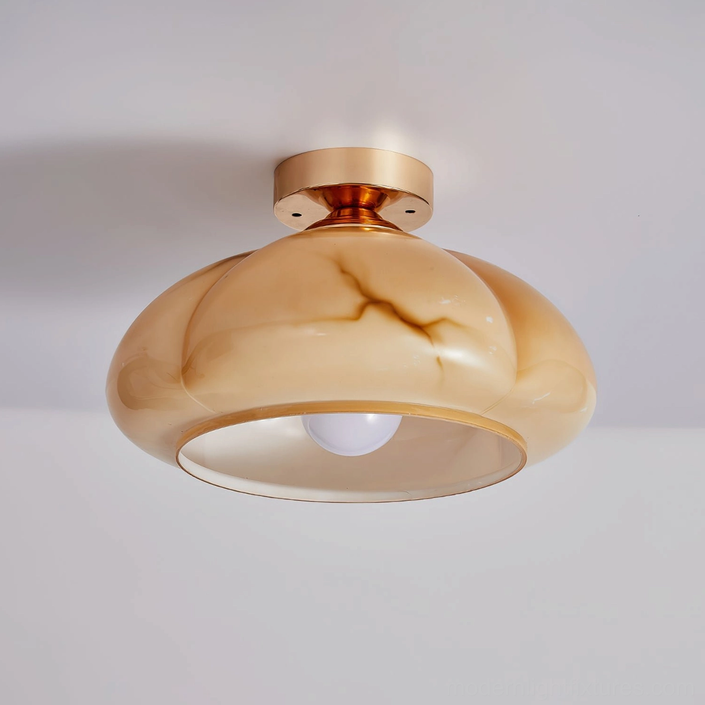 Essence semi-flush ceiling light close-up showing polished brass mounting base and marbled amber glass shade