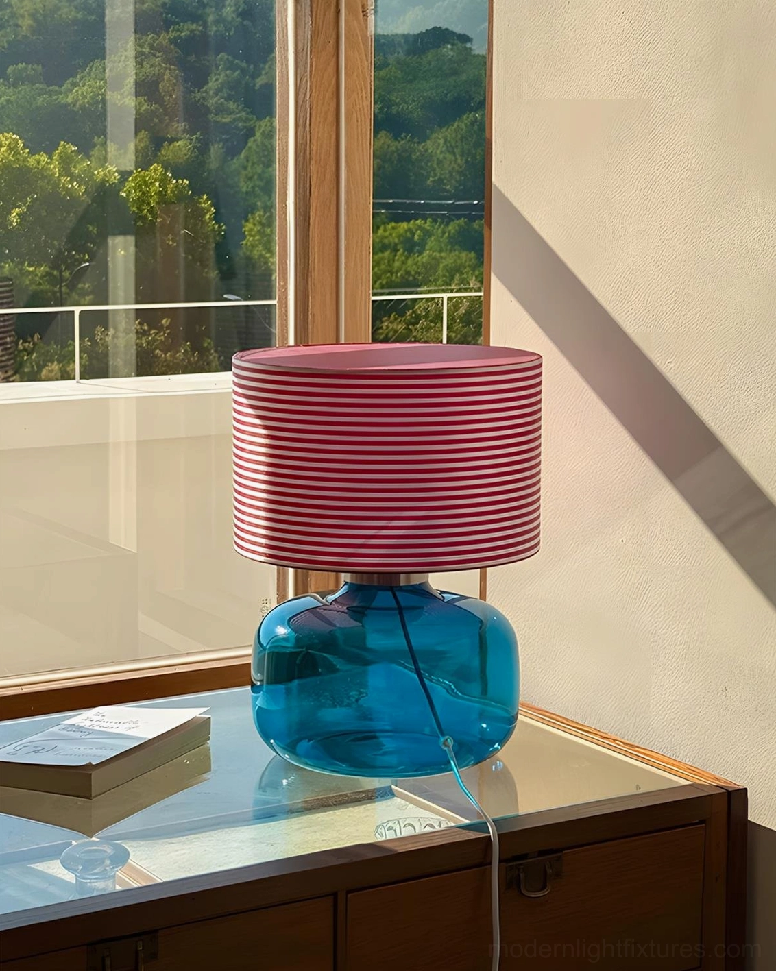 Popello blue glass table lamp three-quarter view on glass wood side table living room window