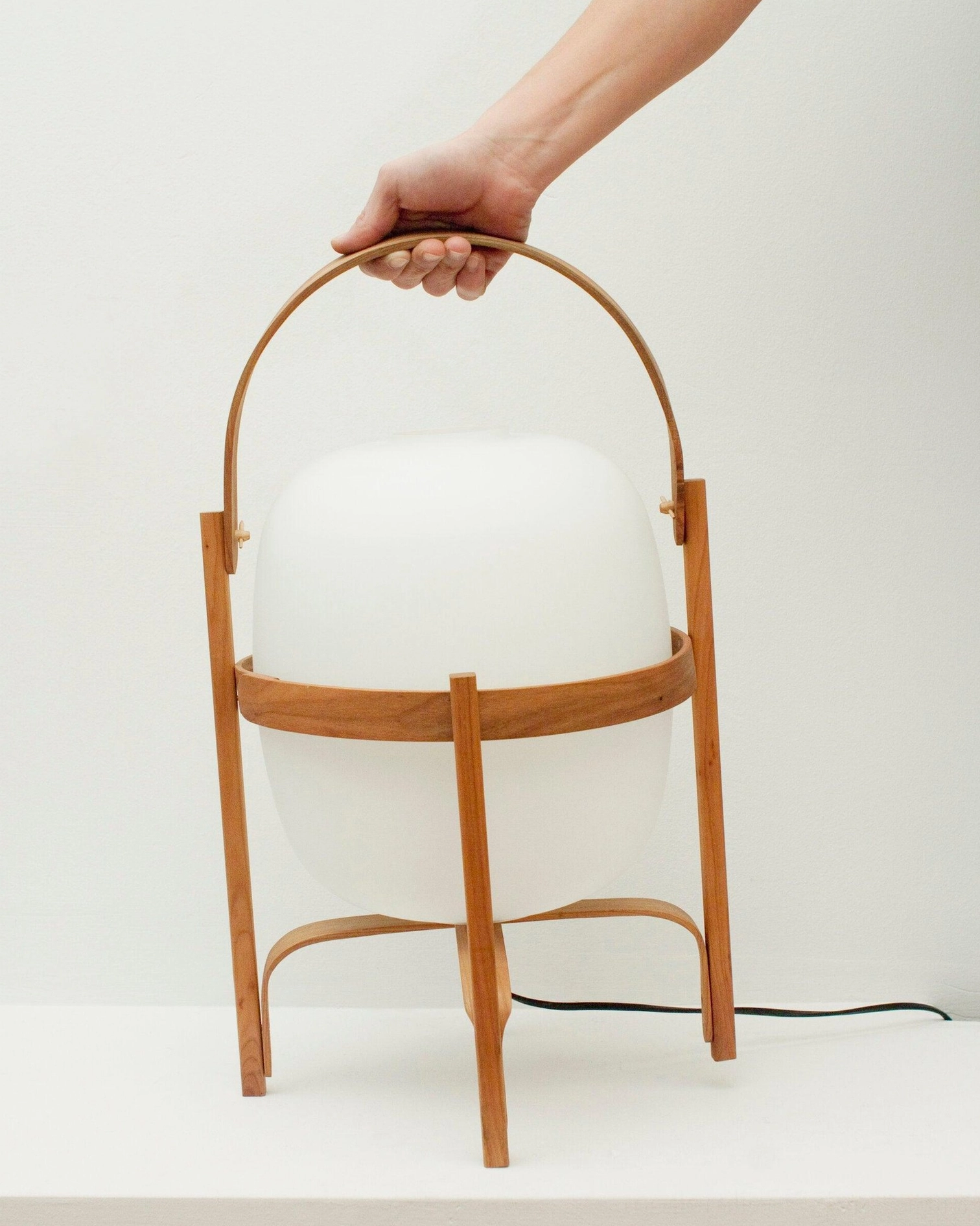Hand holding wooden carry handle of portable lantern glass table lamp