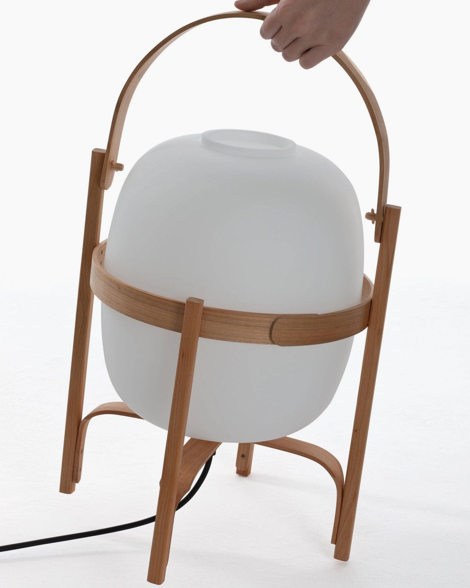 Hand lifting wooden handle of portable lantern glass lamp - showing portability feature