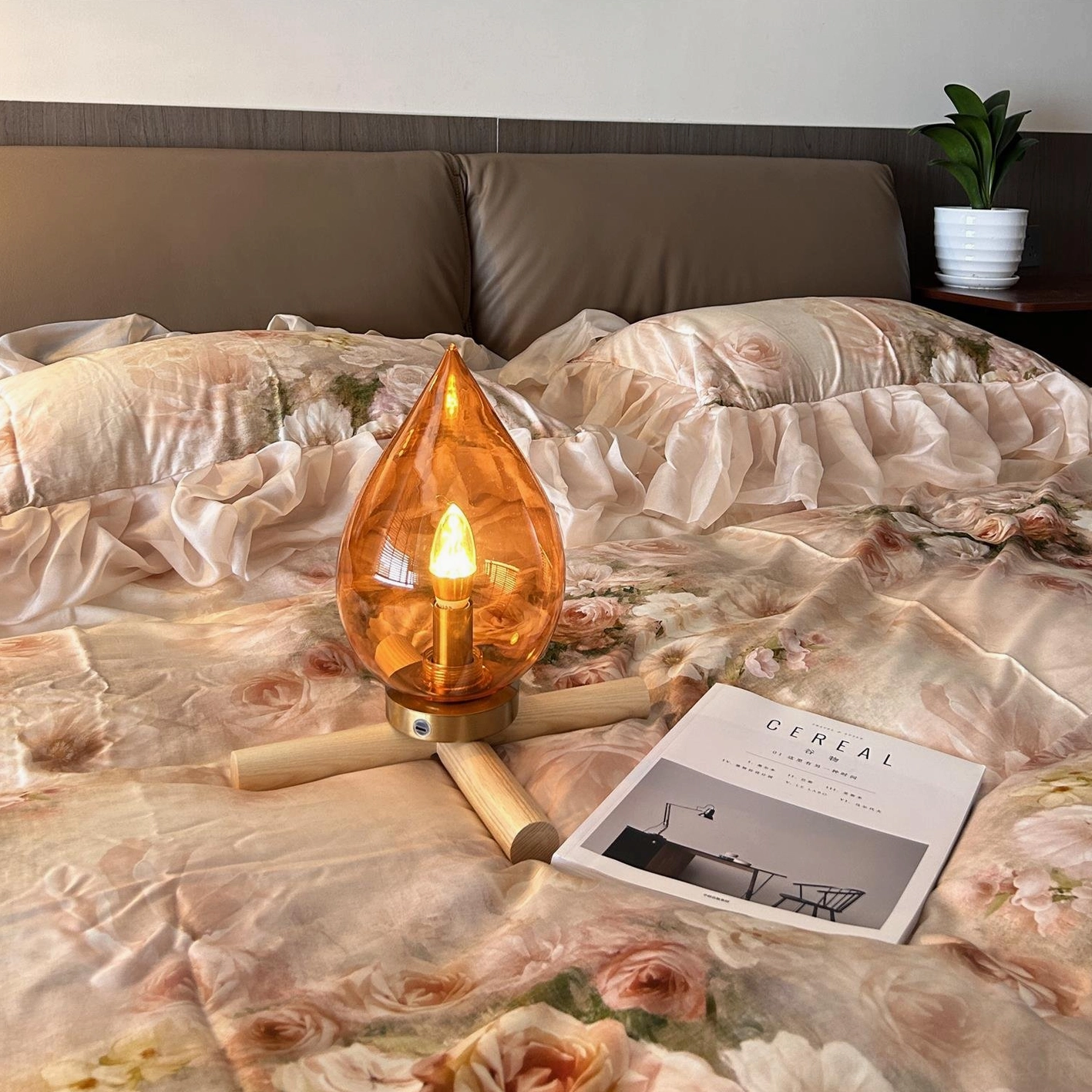 Portable table lamp with warm orange glass, integrated LED technology, lifestyle shot