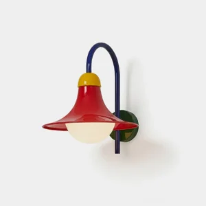 Primora colorblock wall sconce frontal studio view showing blue arched arm, red flared shade, yellow accent cap, and green backplate with opal globe diffuser