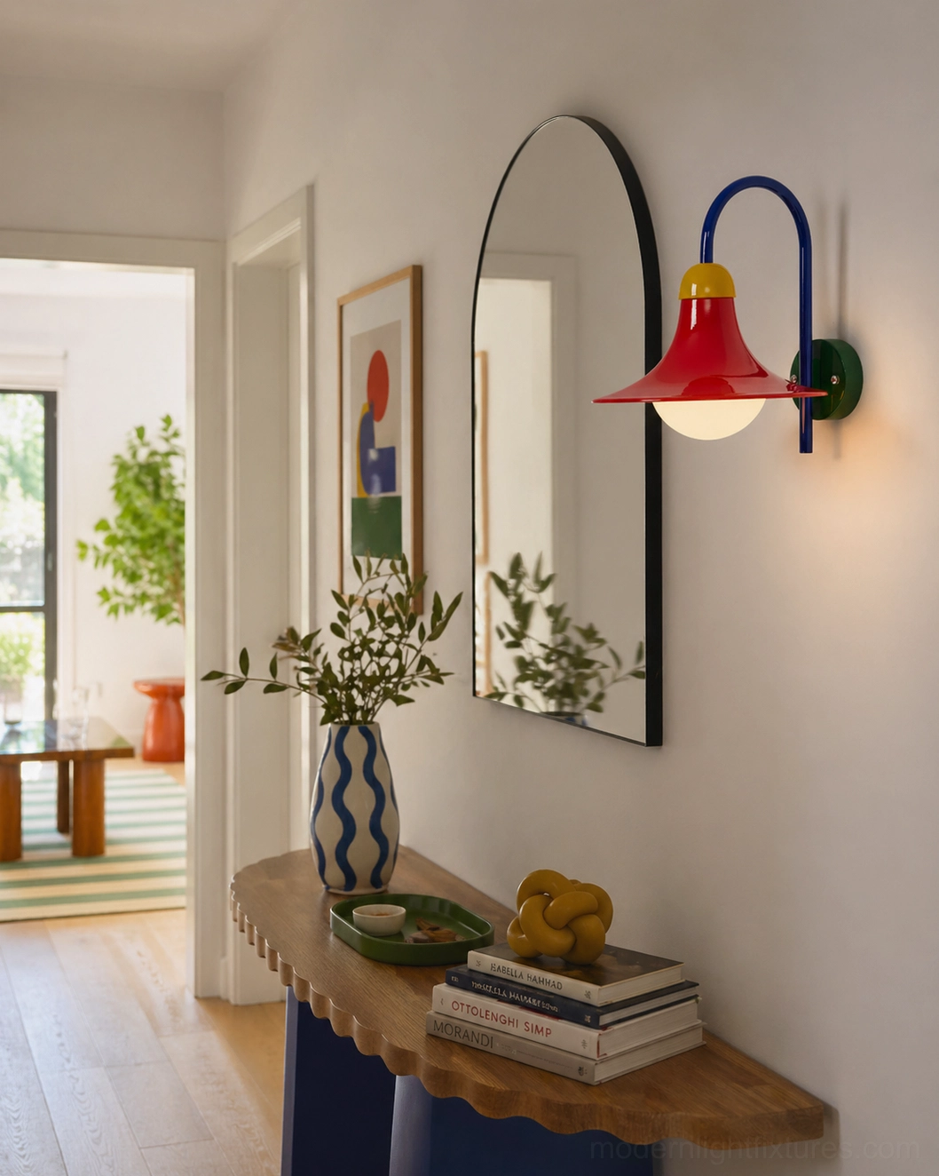 Primora modern wall sconce mounted in residential entryway beside decorative arched mirror for ambient lighting and artistic wall accent