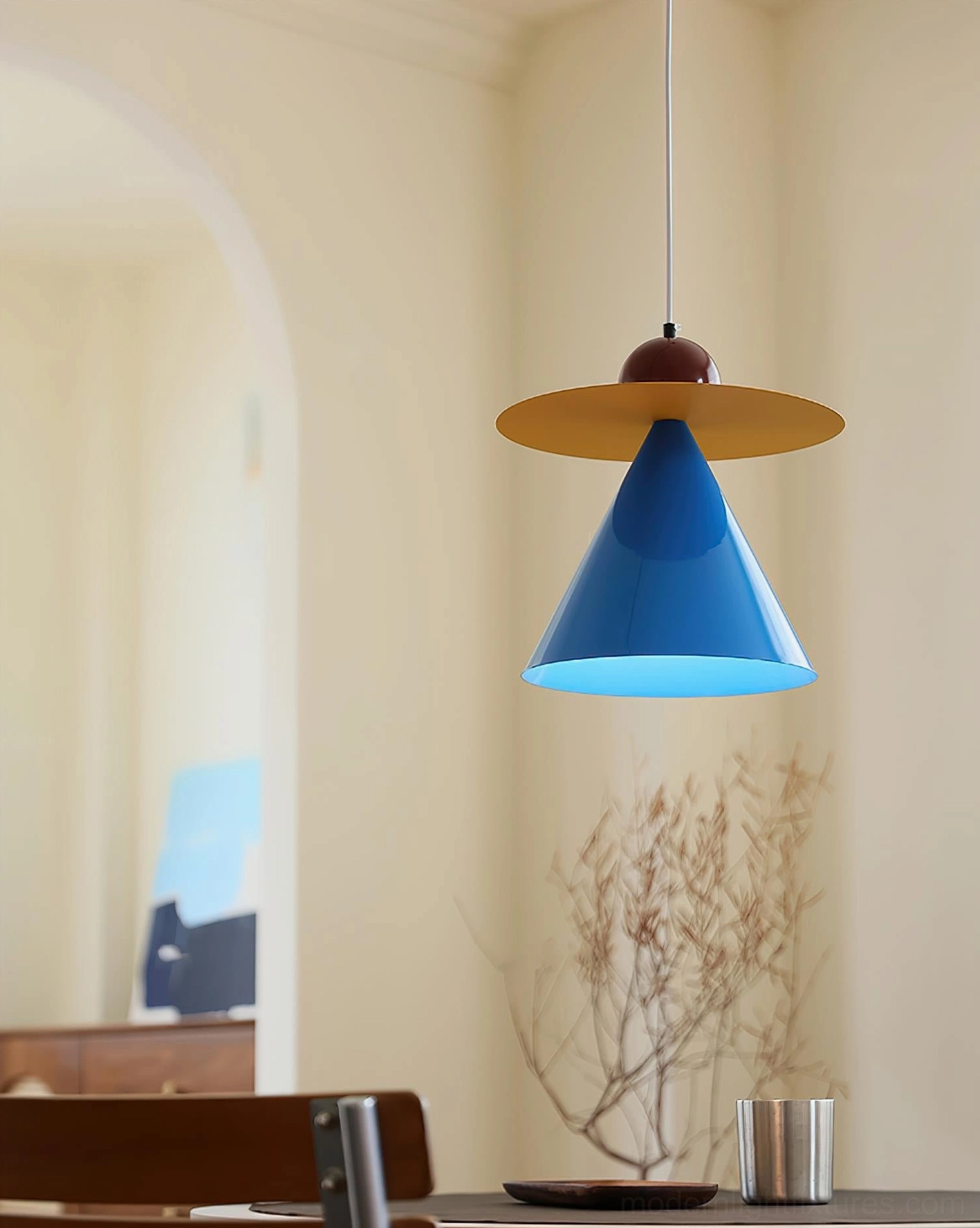 Modern pendant light fixture in minimalist dining area with dried plant decoration
