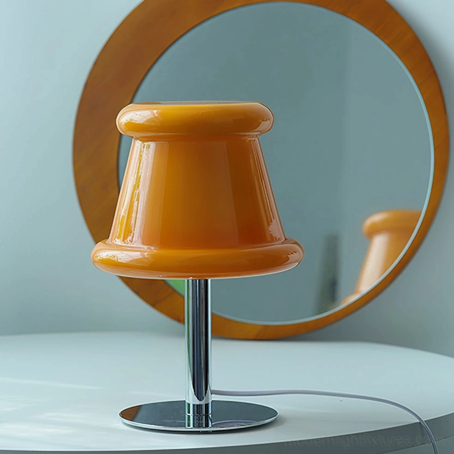 Unlit amber orange pudding glass table lamp on vanity table with round mirror, showing sculptural glass shade and chrome base detail