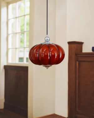 Vintage red pumpkin glass pendant light hanging in warm interior with wooden backdrop