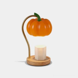 Pumpkin candle warmer lamp with glossy orange shade and brass curved arm on wooden base, front three-quarter view in minimalist studio setting