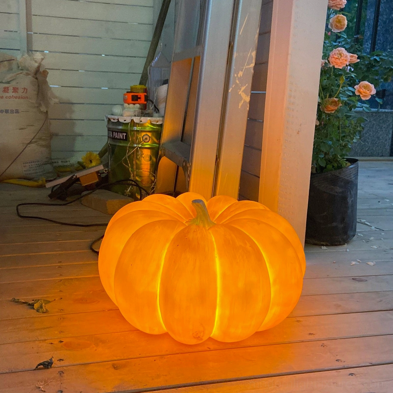 Outdoor pumpkin ambient lamp glowing on wooden patio deck eye level perspective garden lighting