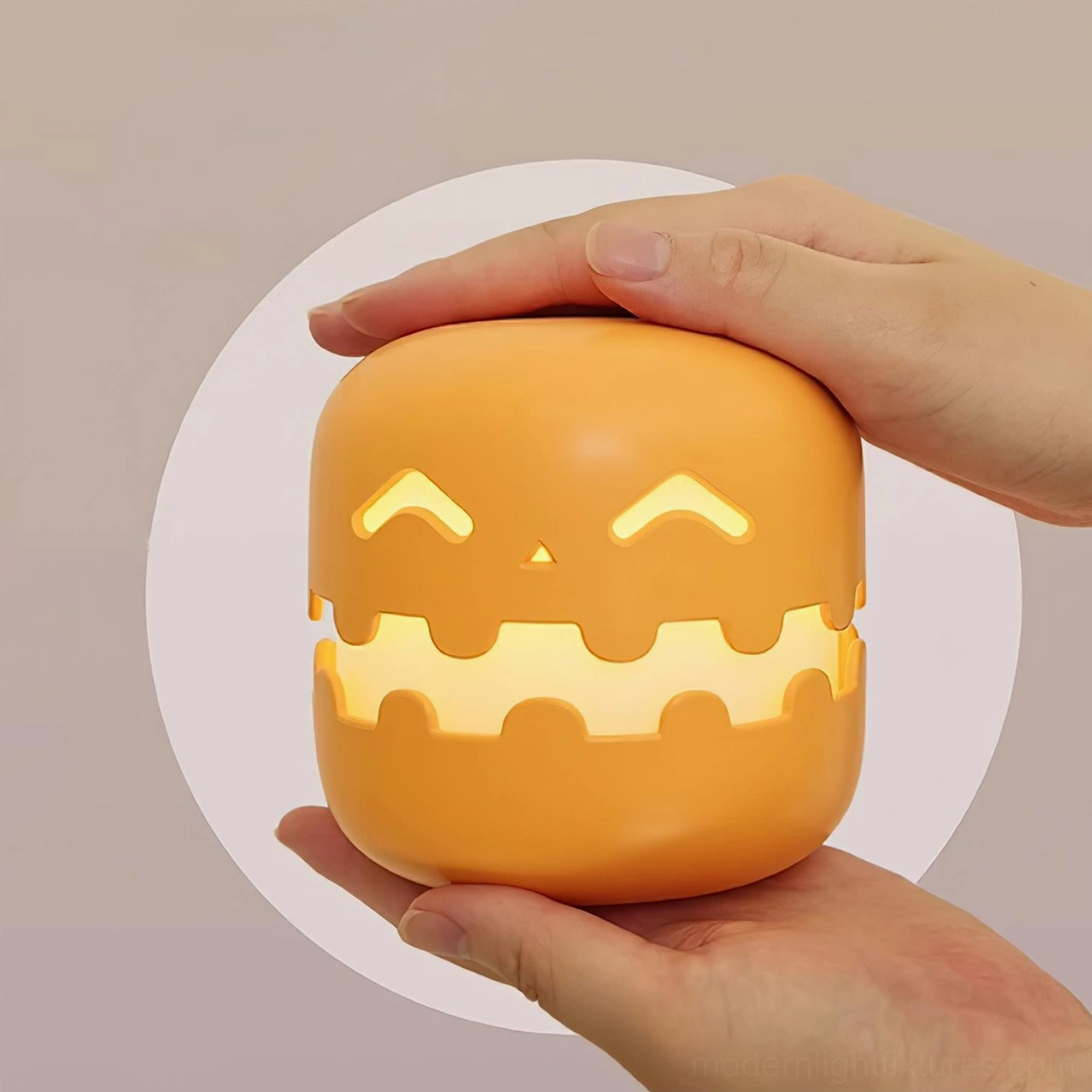 Pumpkin table lamp with squinting expression held in hands, matte orange glowing finish