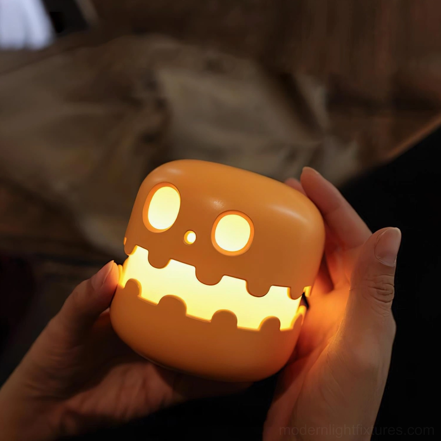 Pumpkin night light held in hands, warm white glow in dim interior environment