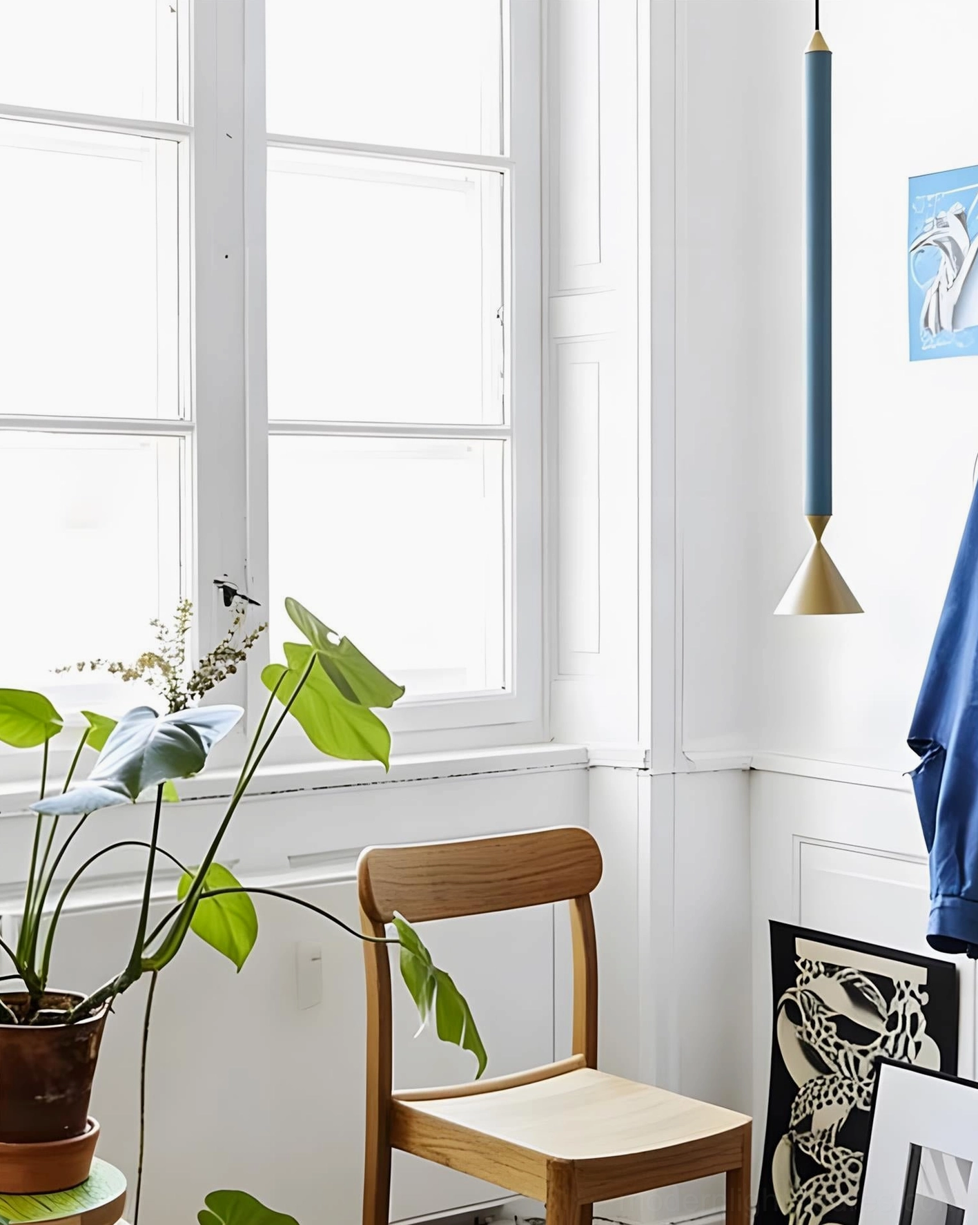 Navy blue cylindrical Pylon pendant with gold cone base beside window, modern residential pendant light fixture