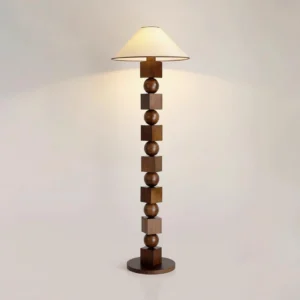 Dark walnut wooden floor lamp with geometric sphere-cube design, eye-level view displaying warm illuminated beige shade and wooden base on light wall background