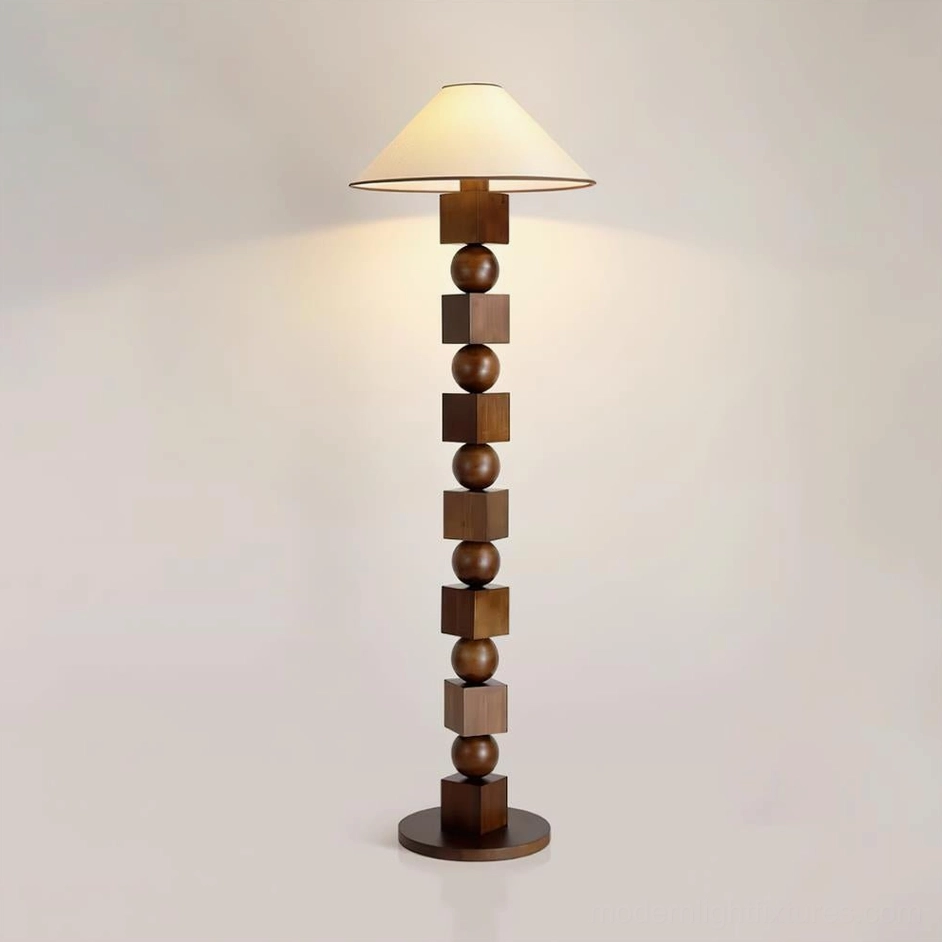 Dark walnut wooden floor lamp with geometric sphere-cube design, eye-level view displaying warm illuminated beige shade and wooden base on light wall background