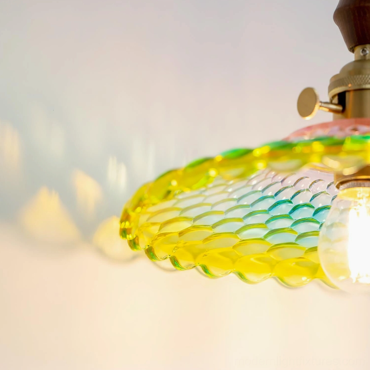 Close-up angled view of Rainbowa glass shade with gradient color transitions and exposed warm filament bulb