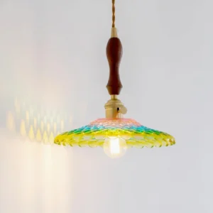 Three-quarter view of Rainbowa pendant lamp showing honeycomb textured glass shade casting colorful light patterns on wall