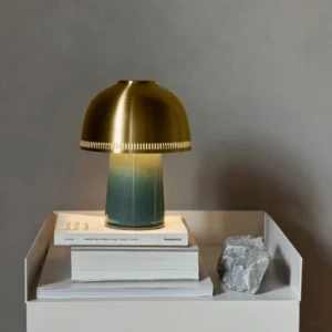 Raku handcrafted ceramic table lamp displayed on minimalist bedside with stacked books and gradient teal base