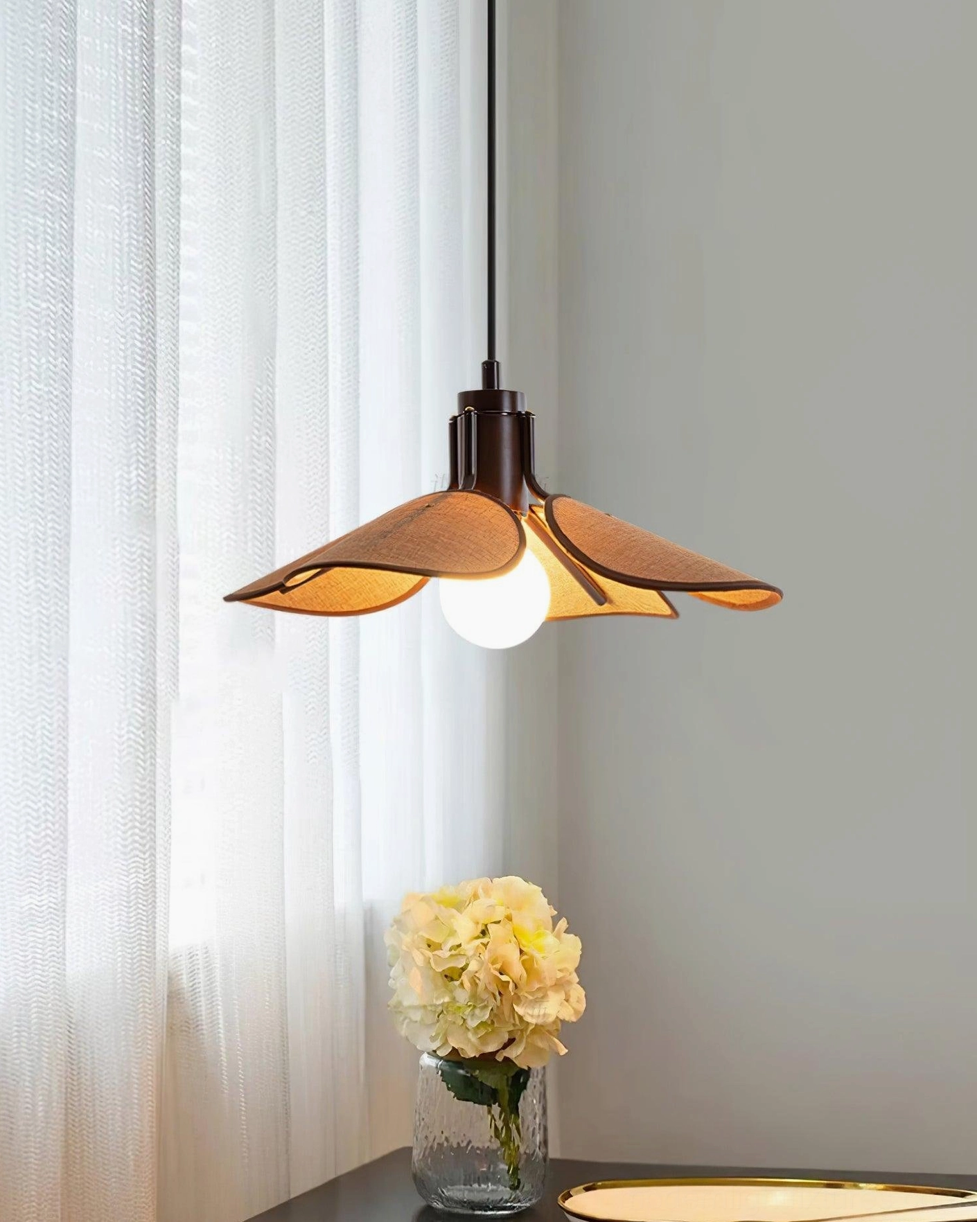 Artisan rattan ceiling pendant with dark suspension cord, side angle view in dining room setting