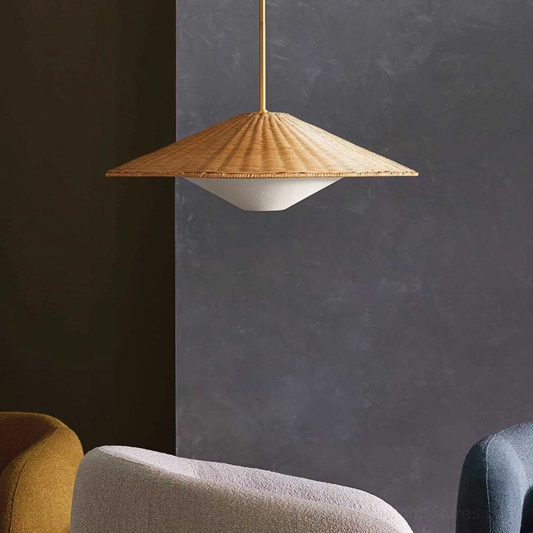 Two-tier woven rattan cone pendant light photographed from low side angle against dark grey textured wall with partial furniture visible