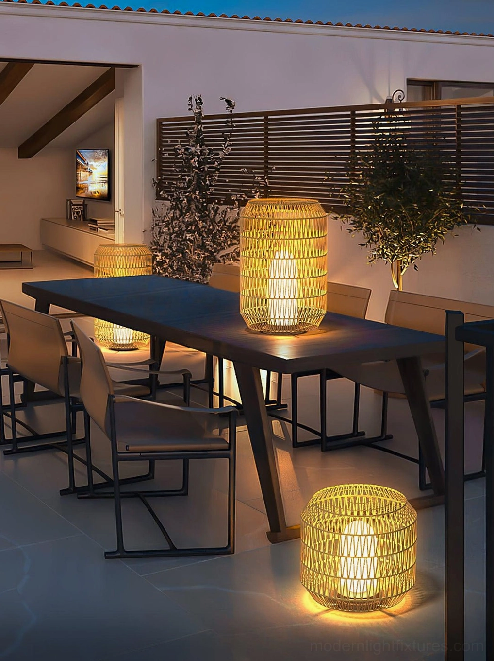 Mixed-size rattan outdoor dining lamps creating warm ambient lighting on nighttime patio