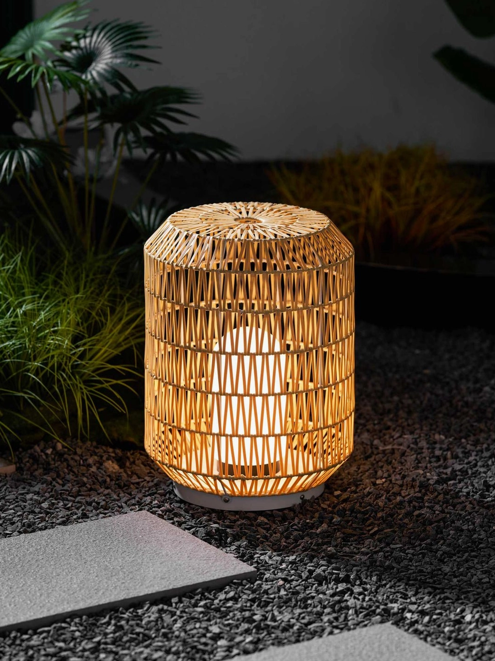 Woven rattan outdoor lamp creating soft filtered light in Scandinavian-inspired outdoor space