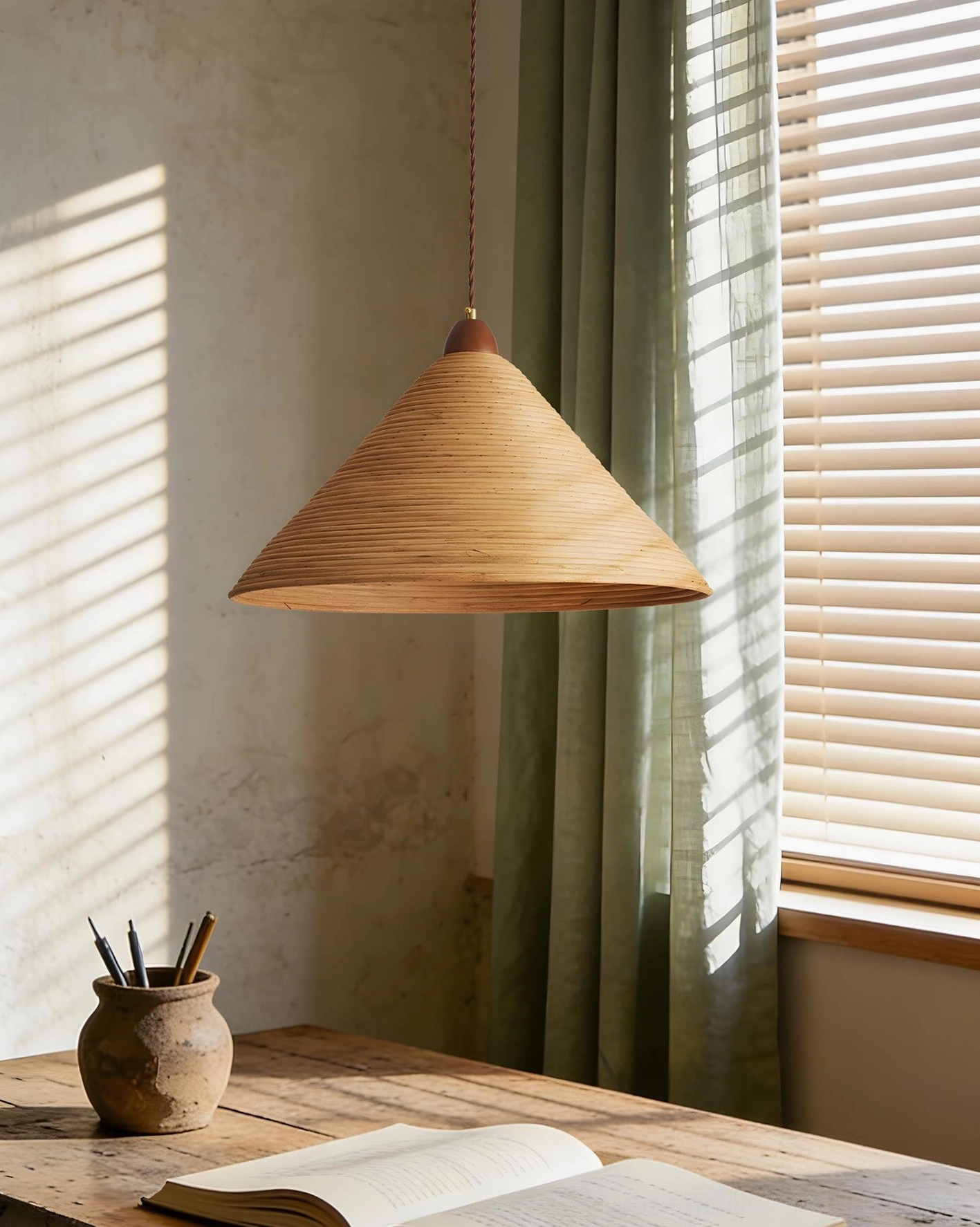 Natural rattan cone pendant light over wooden home office desk with soft window lighting