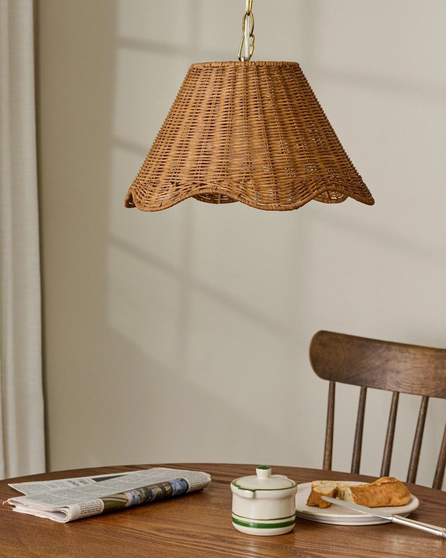 Hand-woven rattan pendant fixture in rustic farmhouse dining nook with natural brown tones and gold hardware