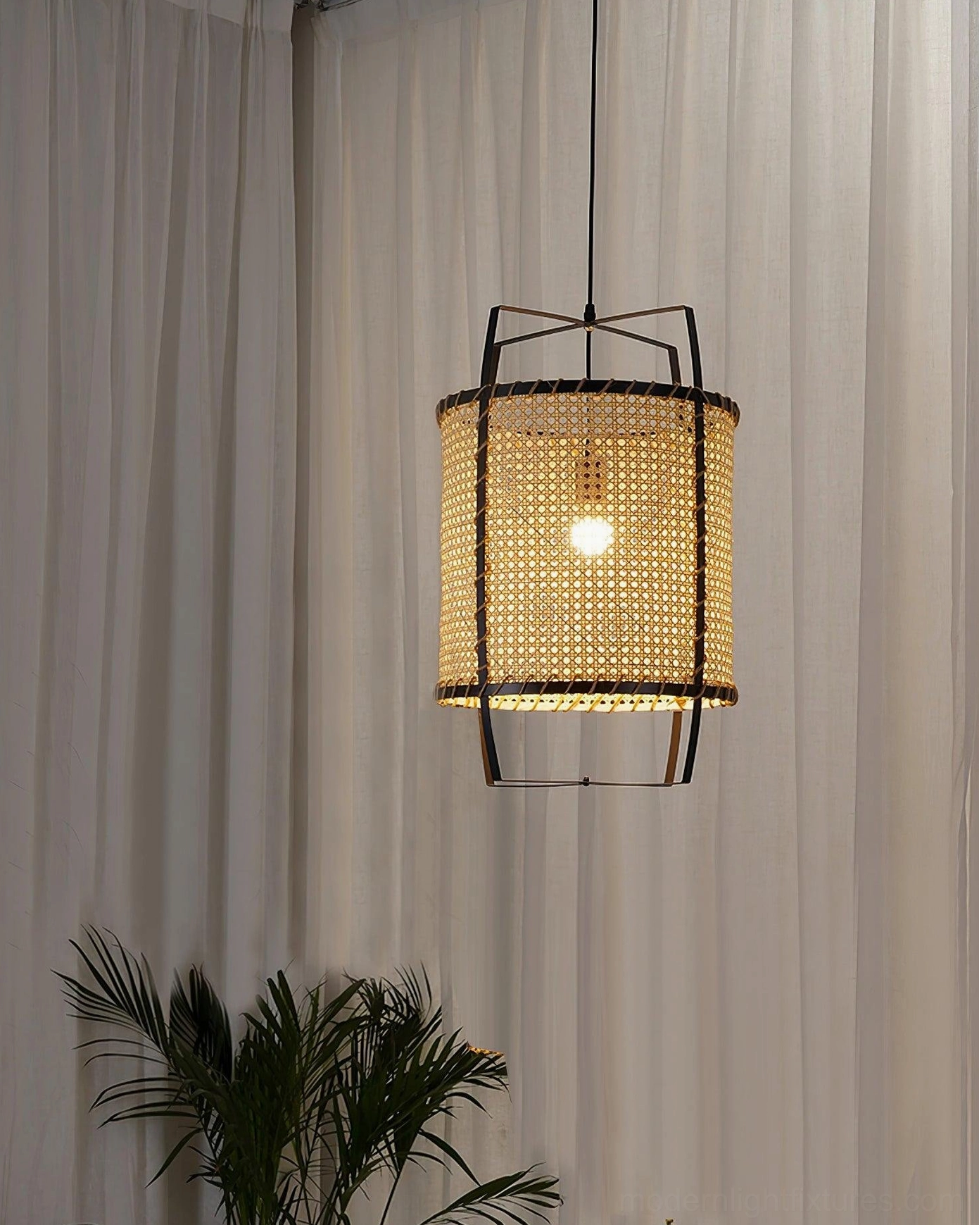 Natural rattan cylinder pendant lamp with black frame in minimalist interior space