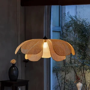 Rattan petal pendant lamp illuminated in modern dining room with window view, creating warm ambient light over dining area with potted plants