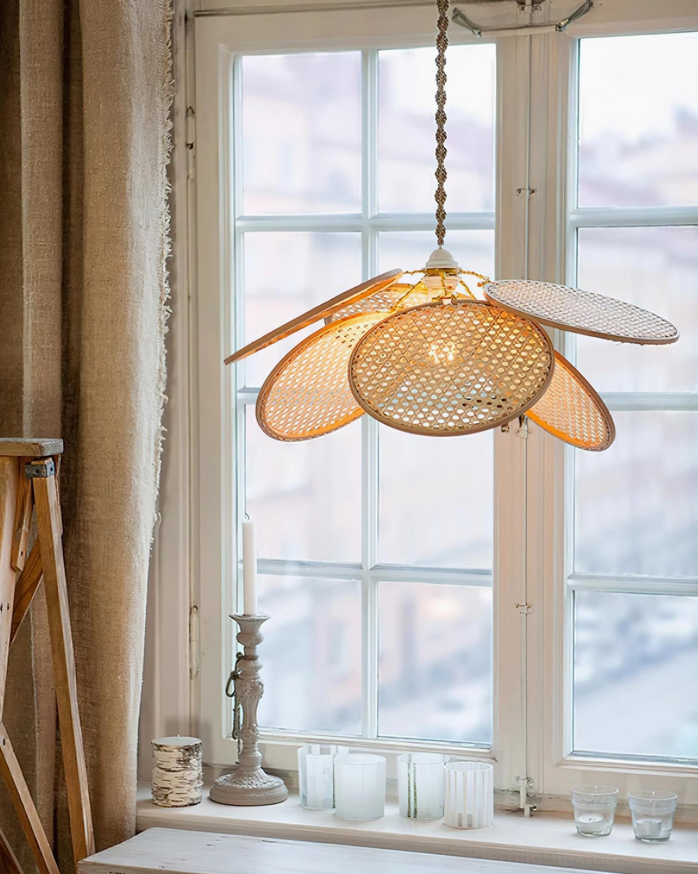 Rattan petal pendant lamp side angled view with braided chain hanging in natural residential window setting