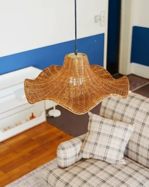 Natural rattan pleated pendant lamp installed in modern living room, showing warm light diffusion through woven shade