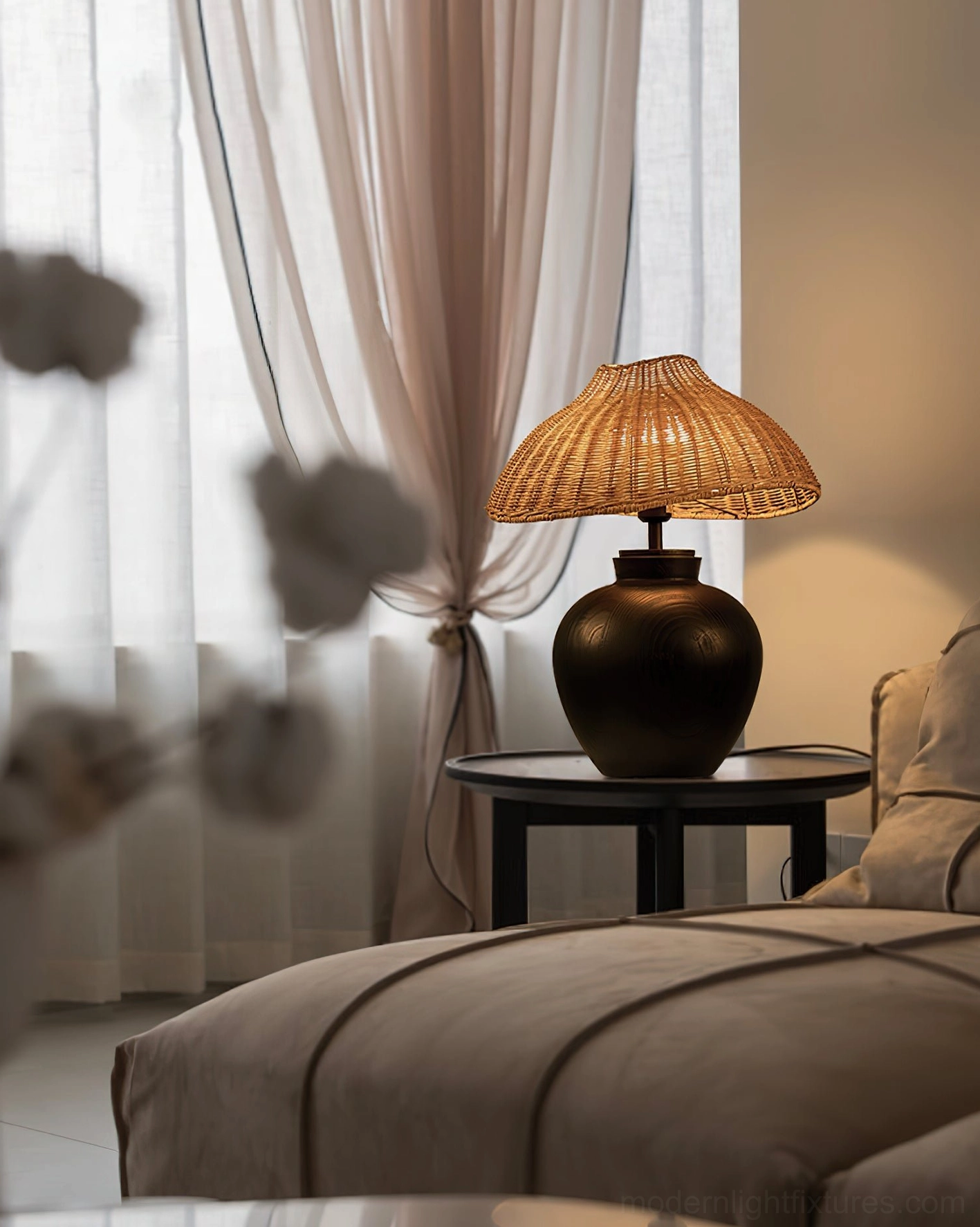 Woven rattan table lamp on black side table in cozy master bedroom, creating intimate bedside lighting