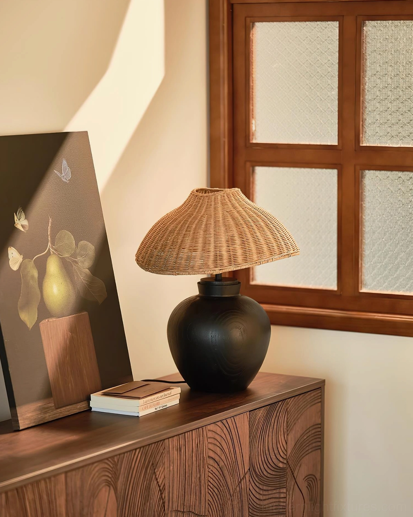 Hand-woven rattan table lamp beside art prints on wooden furniture, boho-modern design inspiration
