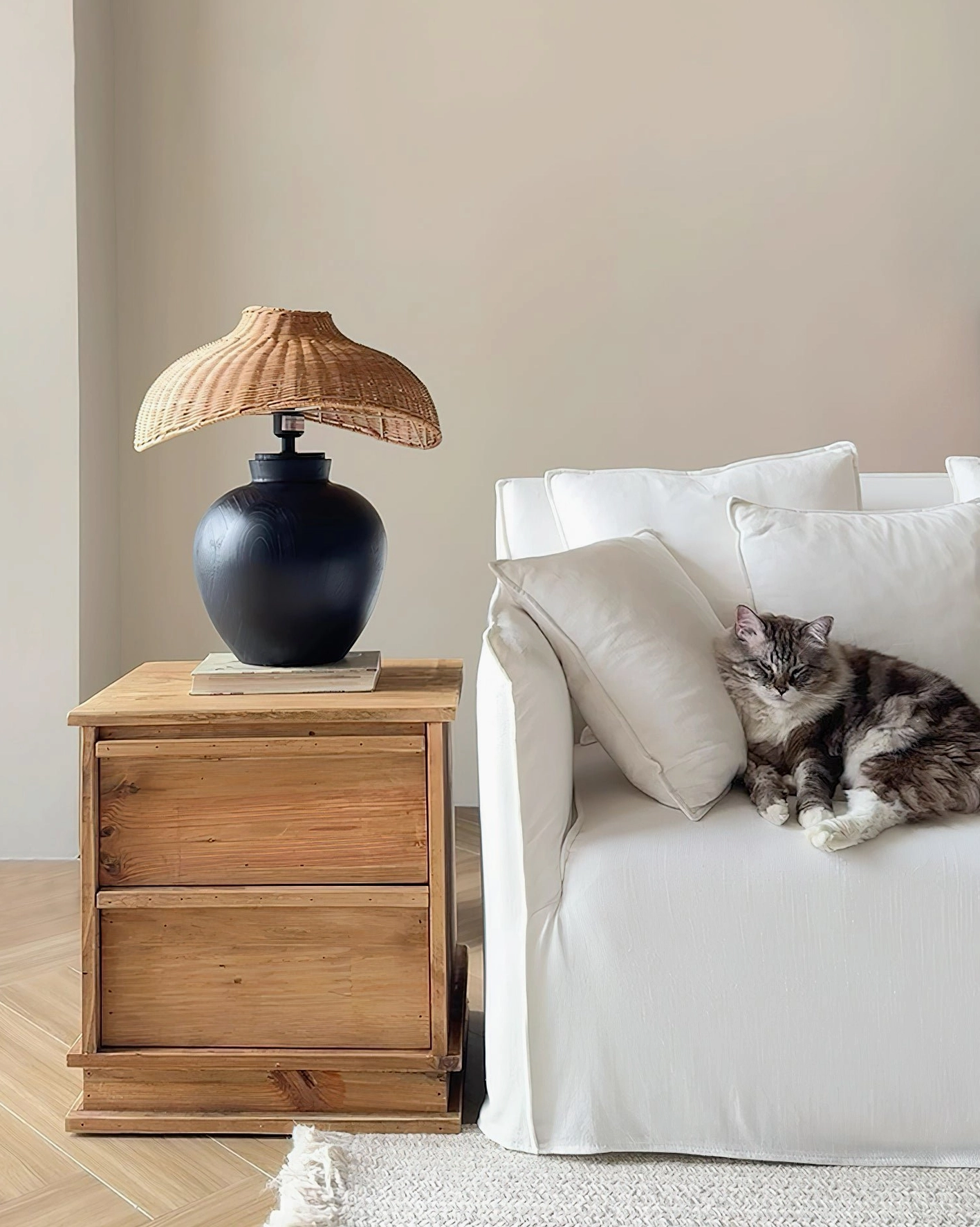 Contemporary rattan table lamp in minimalist living room setting with sofa and side cabinet, warm ambient lighting